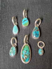 Load image into Gallery viewer, Set of turquoise stone pendants in silver settings on a dark slate background