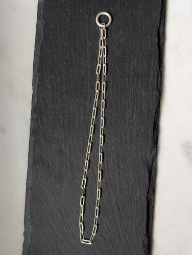Silver chain with a clasp on a black slate surface