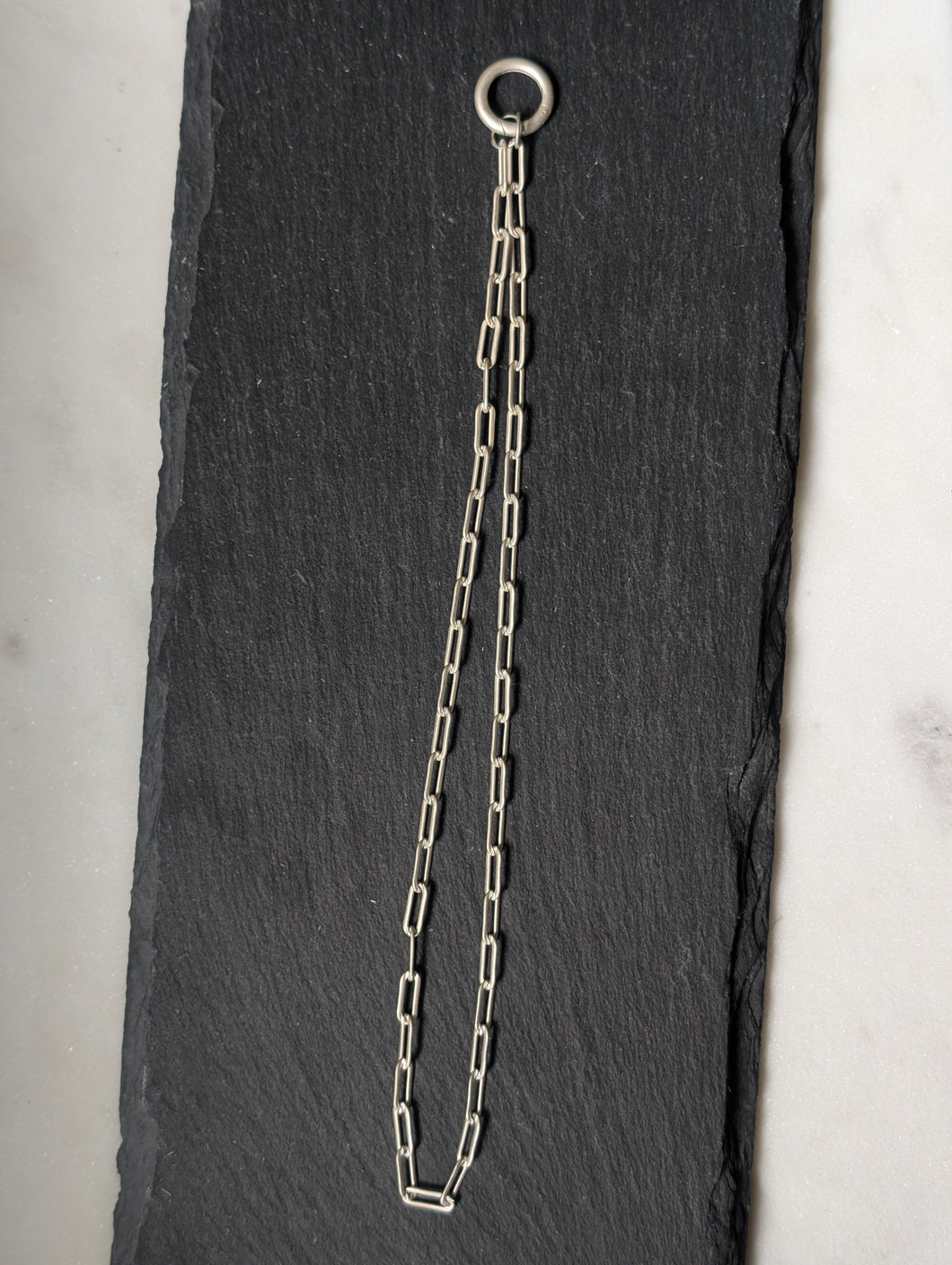 Silver chain with a clasp on a black slate surface